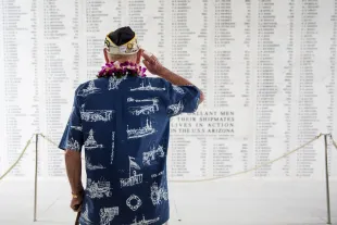 U.S.S. Arizona survivor Lou Conter salutes the Arizona Remembrance Wall during a memorial service marking the 74th Anniversary of the attack on the U.S. naval base at Pearl Harbor (Image via Getty)