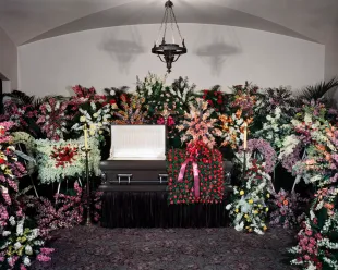 Open Casket Funeral Home Viewing Parlor Surrounded By Unusual Number Of Fantastic Ornate Floral Bouquet Arrangements (Image via Getty)