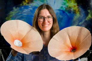 Jocelyn Read, a professor of Physics at California State University Fullerton displays model of the space-time around a neutron star, left, and black hole, right  (Image via Getty)