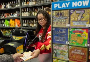 Hawthorne, CA - December 1: William Adelman hands his lottery tickets to cashier Maggie Duran at Bluebird Liquor on Monday, Dec. 1, 2025 in Hawthorne, CA. The Powerball jackpot has reached $740 million after no weekend winner was chosen. (Juliana Yamada / Los Angeles Times via Getty Images)