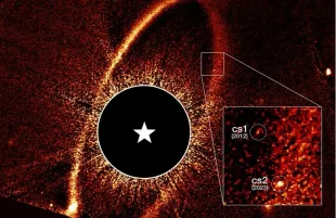 This composite Hubble Space Telescope image shows the debris ring and dust clouds cs1 and cs2 around the star Fomalhaut (Image via NASA)