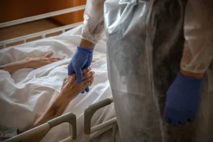 Hospital Director, Doctor Yutaka Kobayashi, holds the hand of a 94-year-old patient(Image via Getty)
