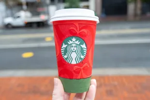 Person's hand holding red and green colored Starbucks holiday cup showing 2025 design, San Francisco, California, November 20, 2025. (Photo by Smith Collection/Gado/Getty Images)
