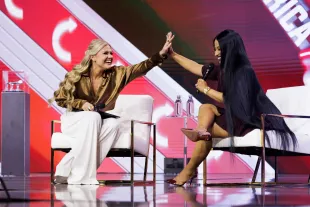 Erika Kirk and Nicki Minaj high-five during an interview on the final day of Turning Point USA's annual AmericaFest conference (Image via Getty)