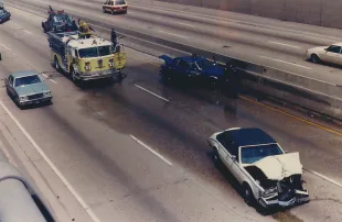 Firefighters clearing wrecked cars from the highway during a major car accident, Michigan, 1987 (Image via Getty)