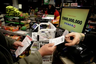 CHICAGO, IL - JANUARY 9 :  A customer receives Powerball tickets from a clerk at a 7-Eleven store January 9, 2016 in Chicago, Illinois. The Powerball Jackpot Surged to a record $900 Million in 44 States, Washington D.C., Puerto Rico, and the US Virgin Islands before tonight's drawing. (Photo by Joshua Lott/Getty Images)