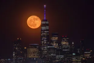 NORTH ARLINGTON, NJ - MAY 24: A 96 percent illuminated waning gibbous Flower Moon rises behind the skyline of lower Manhattan and One World Trade Center in New York City on May 24, 2024, as seen from North Arlington, New Jersey.  (Photo by Gary Hershorn/Getty Images)