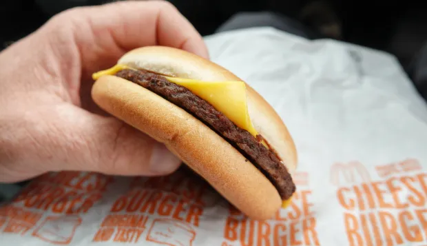 BRISTOL, UNITED KINGDOM - JULY 27: A man eats a McDonald's cheeseburger on July 27, 2022 in Bristol, England. McDonald’s has announced that the price of a cheeseburger will increase for the first time in 14 years blaming soaring costs and said other big price increases were on the horizon. The increases come as the UK faces a cost of living crisis, as inflation hits a near-30-year high, the war in Ukraine puts pressure on food prices and rising energy bills squeeze household incomes still further. To add to the misery, many UK households face a further rises in home energy prices as energy price caps are raised.  (Photo by Matt Cardy/Getty Images)