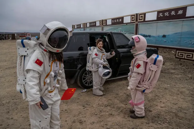 Tourists wear rented astronaut costumes while visiting Volcano #6 of the the Ulan Hada volcano cluster during the Golden Week holiday on October 4, 2021 near Ulan Qab, Inner Mongolia Autonomous Region, China. The volcano cluster, which has seven volcanos, saw its last eruptions more than 10,000 years ago and is a popular tourist destination. (Photo by Kevin Frayer/Getty Images)