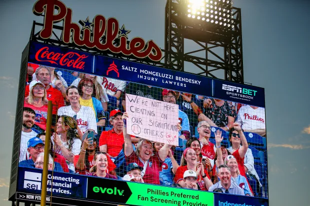PHILADELPHIA, PENNSYLVANIA - JULY 18: A fan holds up a sign during a kiss cam segment in the game between the Philadelphia Phillies and the Los Angeles Angels at Citizens Bank Park on July 18, 2025 in Philadelphia, Pennsylvania. The sign references the Astronomer CEO, Andy Byron, who was seen on a kiss cam during a Coldplay concert that led him to resign from the company. (Photo by Isaiah Vazquez/Getty Images)